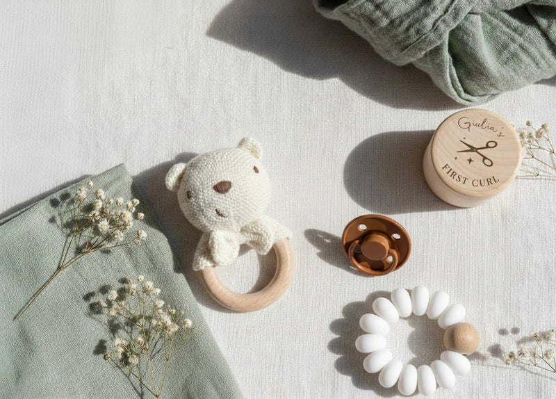 Montessori baby registry essentials Malta: Crochet bear rattle, silicone teether, and wooden keepsake box on neutral linen.