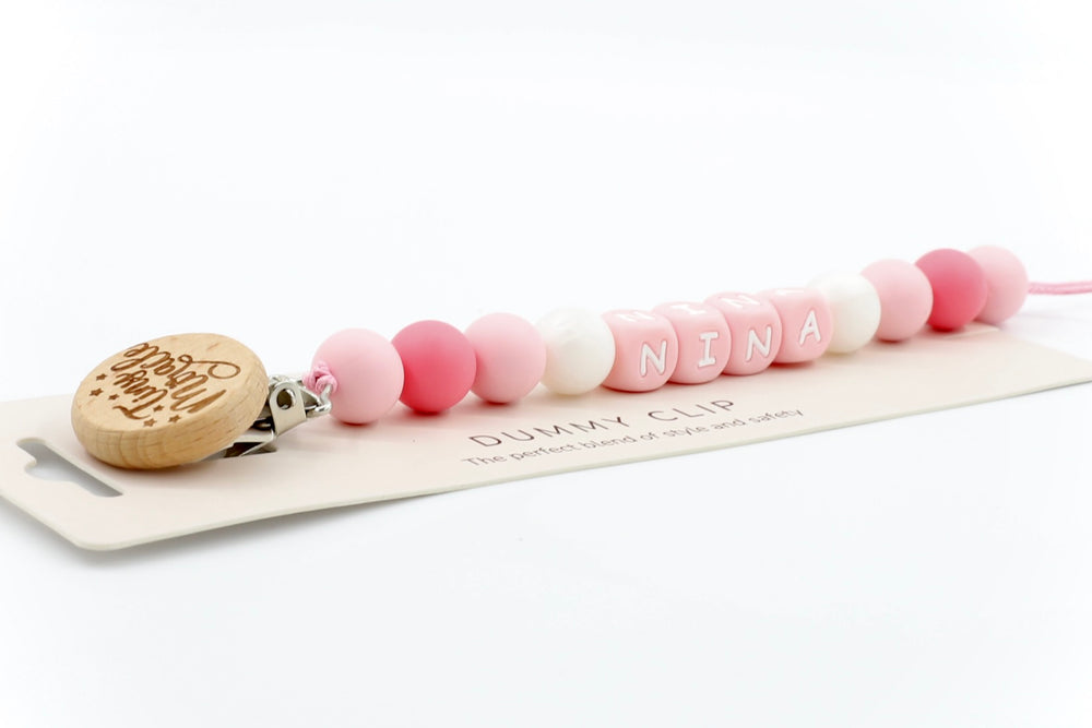 Little Nibbles dummy clip in blush pink and white, personalised with name NINA and finished with engraved wooden clasp