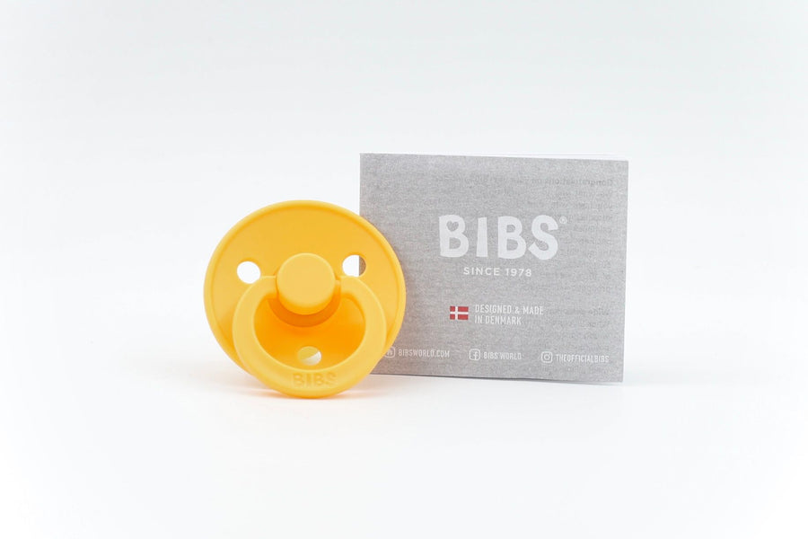 BIBS Colour dummy in Sun Kissed yellow with round natural rubber teat, shown with branded grey packaging on white background