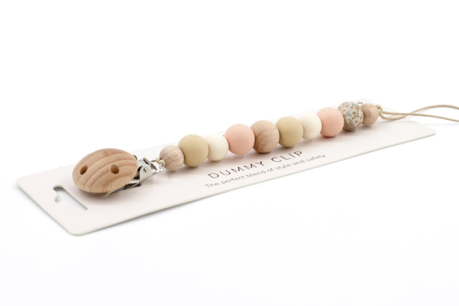 Velvet Sands Dummy Chain in peach, cream, and beige tones, with smooth silicone and wooden beads and a rounded wooden clip, laid on branded packaging.