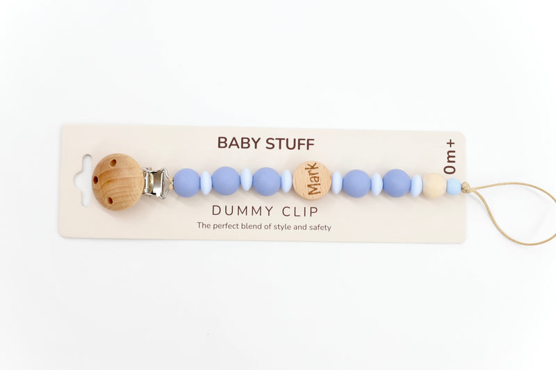 Top down shot of a twilight & baby blue personalised dummy clip with name ‘Mark’ engraved on wooden bead, made from soft silicone and safe for newborn use.