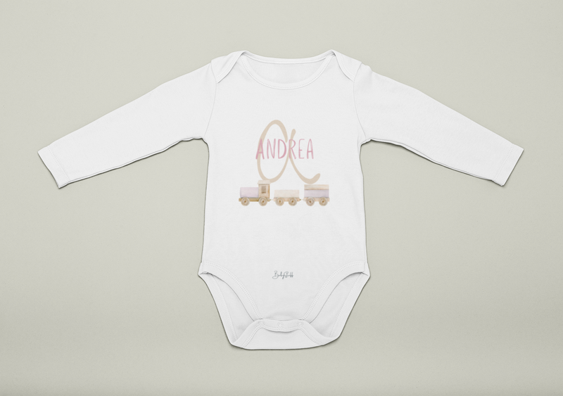 White baby onesie with pink 'Andrea' printed on it against a beige background