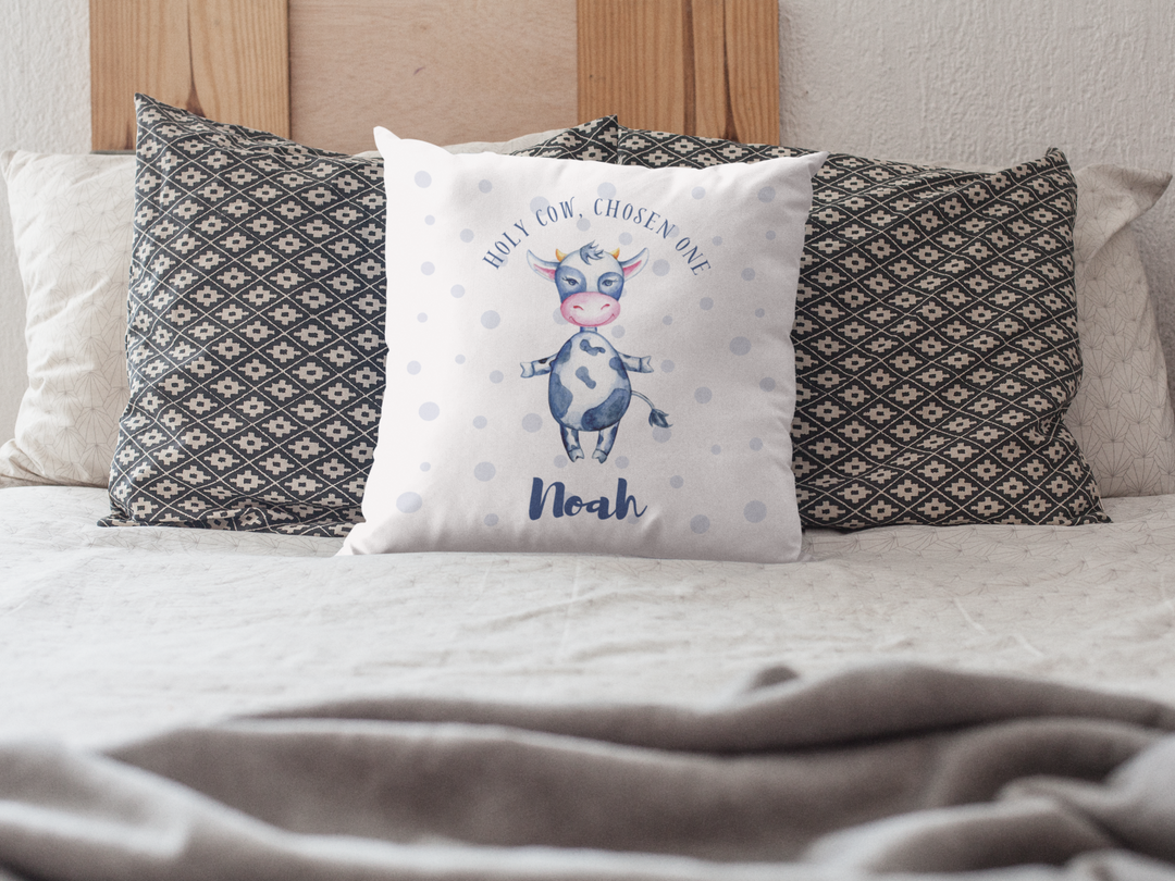 Mosaic Cow cushion baring slogan, "Holy Cow, Chosen one" and personalised baby name laying on a bead