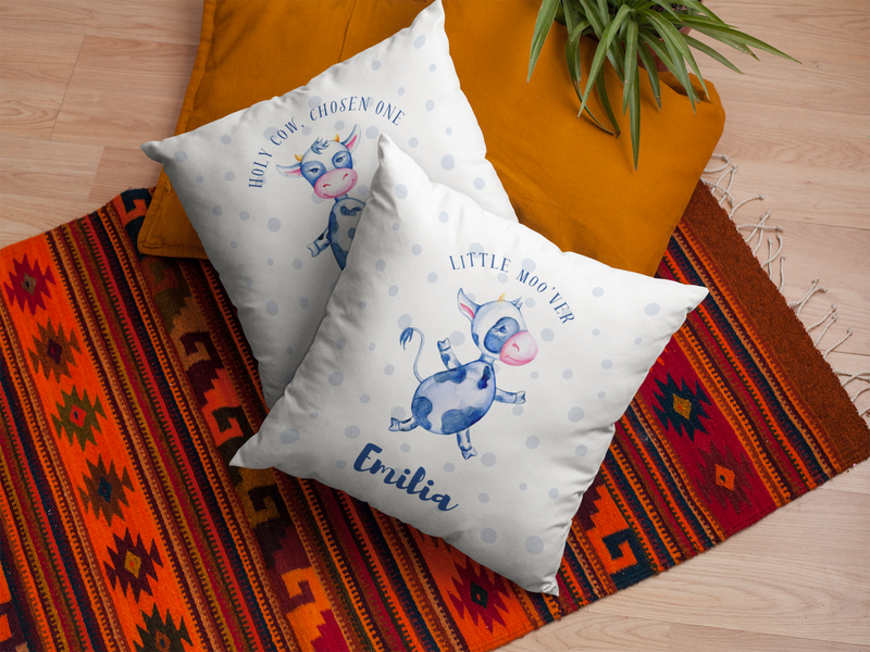 Mosaic Cow Cushion with slogan "Little Moo'ver" and personalised name next to another cushion on a red rug.